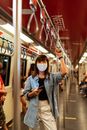一名女子在地铁列车上戴着口罩使用智能手机，以促进出行安全