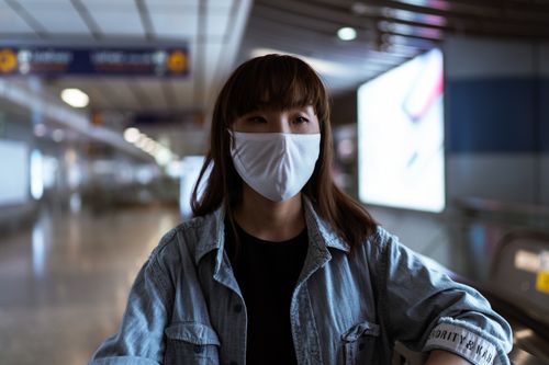 Free Asian woman wearing a face mask in a subway station, focusing on pandemic safety. Stock Photo