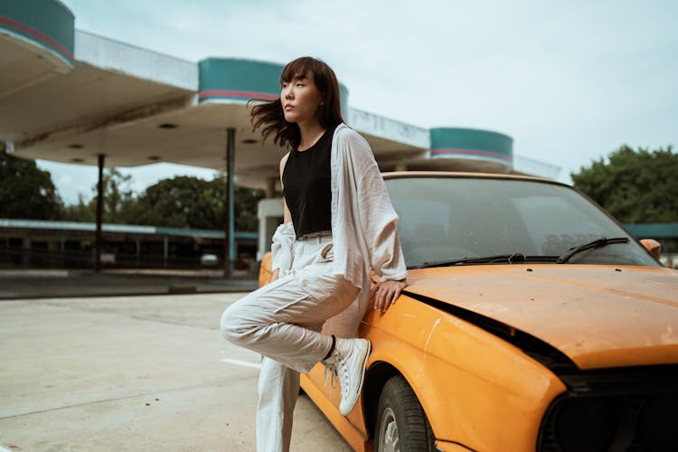 Asian Model Standing Leaned On Retro Auto In Parking Lot