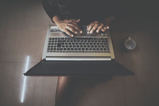 Aerial shot of a person typing on a laptop with a nearby mug. Perfect for technology and lifestyle themes.