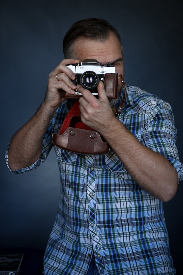 Anonymous Man Taking Photo On Retro Camera In Studio