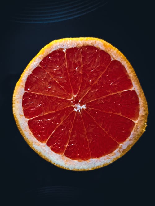 Top view of slice of fresh ripe juicy grapefruit placed on black surface