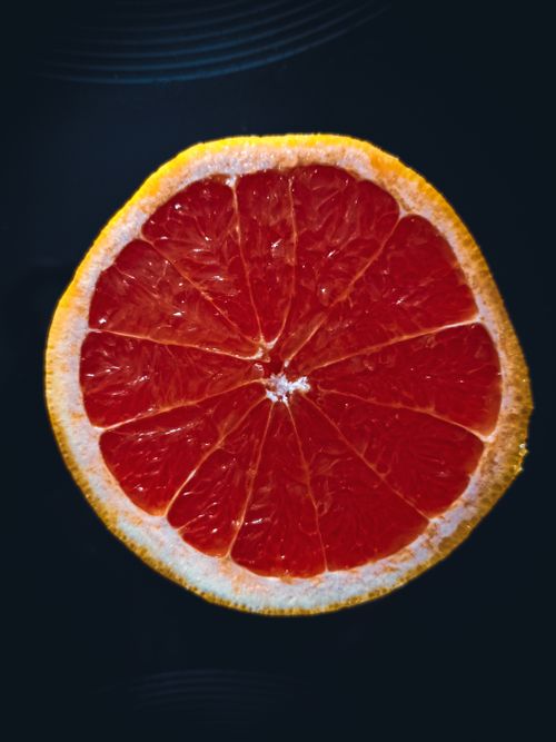 Free Top view of slice of fresh ripe juicy grapefruit placed on black surface Stock Photo