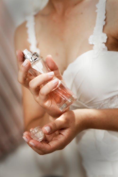 Free Woman in White Dress Holding Perfume Bottle Stock Photo