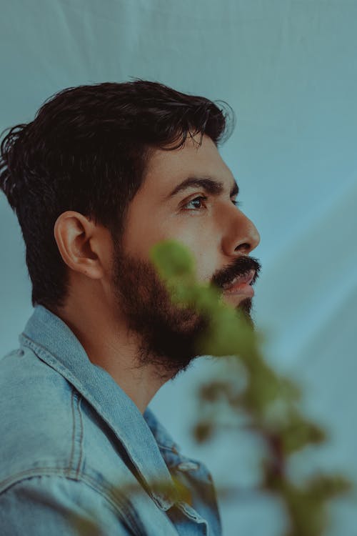 Man in Gray Hoodie With Green Plant in His Mouth