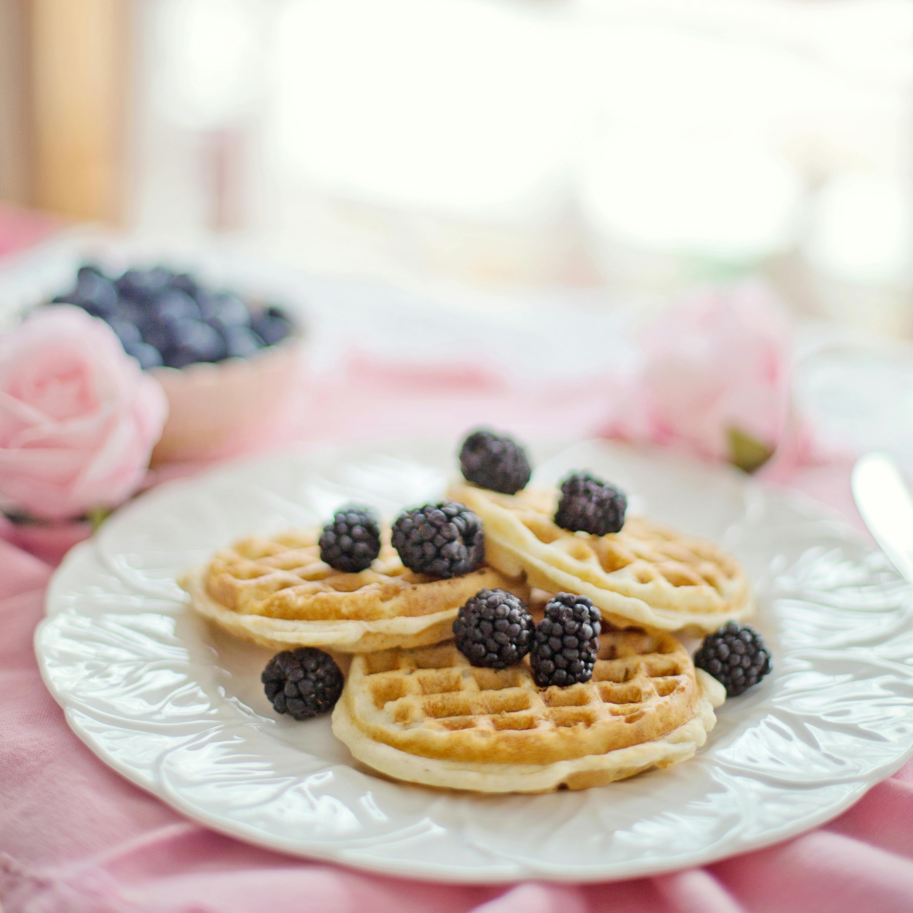 Close-up of waffles with fresh blackberries on a white plate, perfect for breakfast.