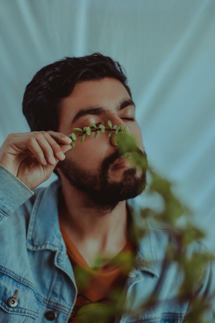 A bearded man poses with a green plant, evoking a natural, serene atmosphere.