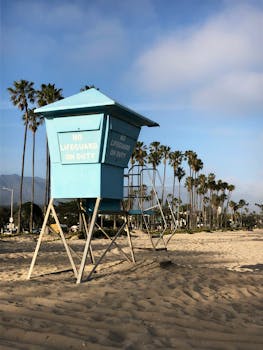 A serene view of Santa Barbara beach with a lifeguard tower and palm trees, captured on a sunny day.