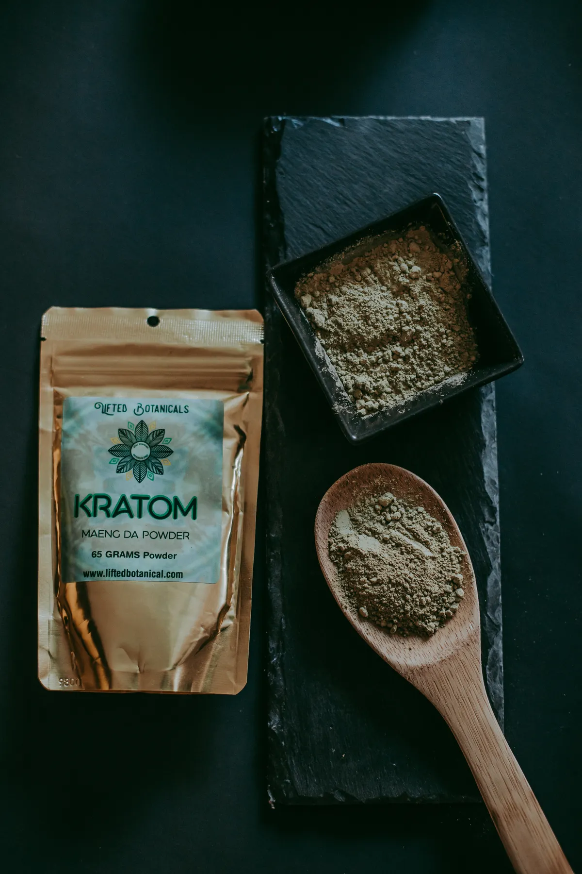 Kratom powder in a bowl with a wooden spoon on a dark surface
