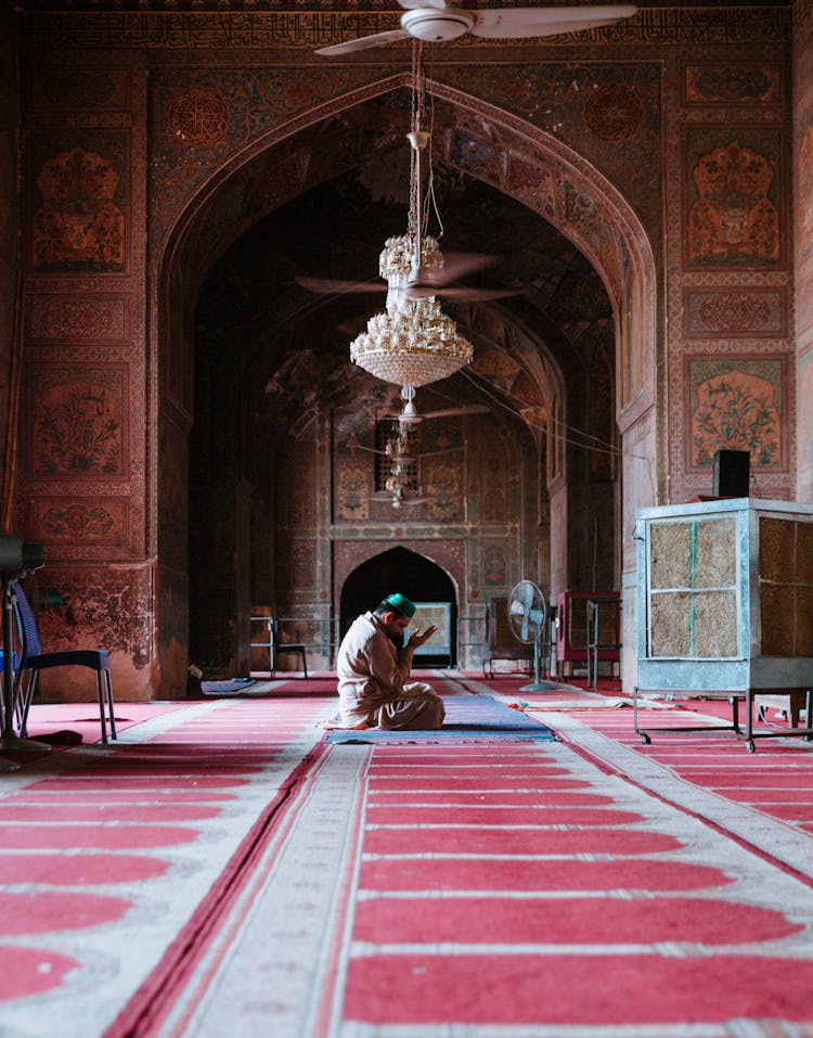 Man Praying On A Rug Under A Chandelier