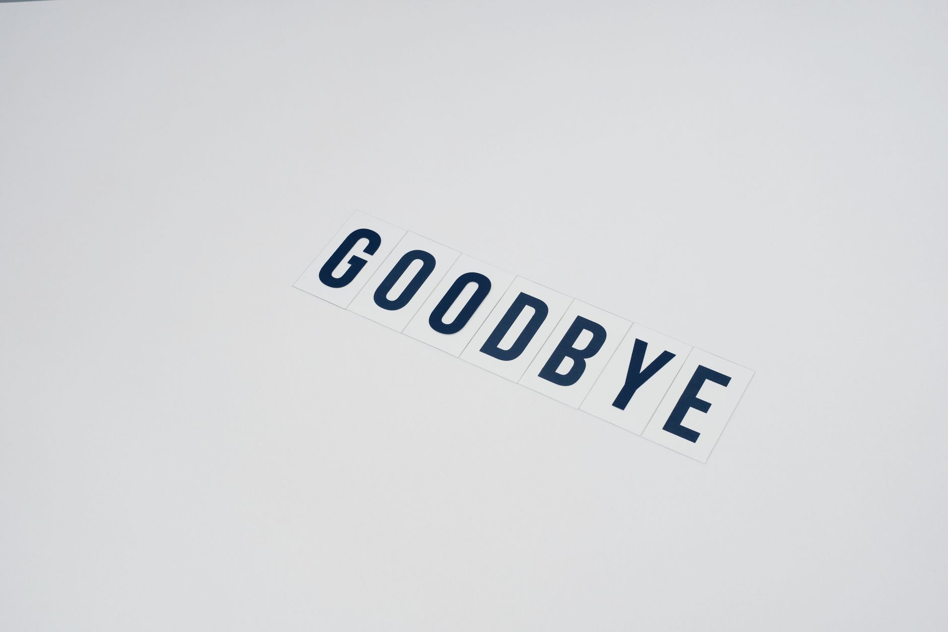Simple typography displaying the word goodbye on a clean white background, offering ample copy space.