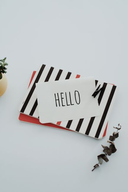 Fotomural Una tarjeta de felicitación minimalista con 'hola' sobre una superficie rayada, elegante y con estilo.
