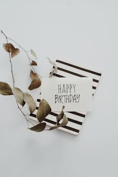 一张以条纹为背景、饰有干桉树叶的极简主义生日贺卡