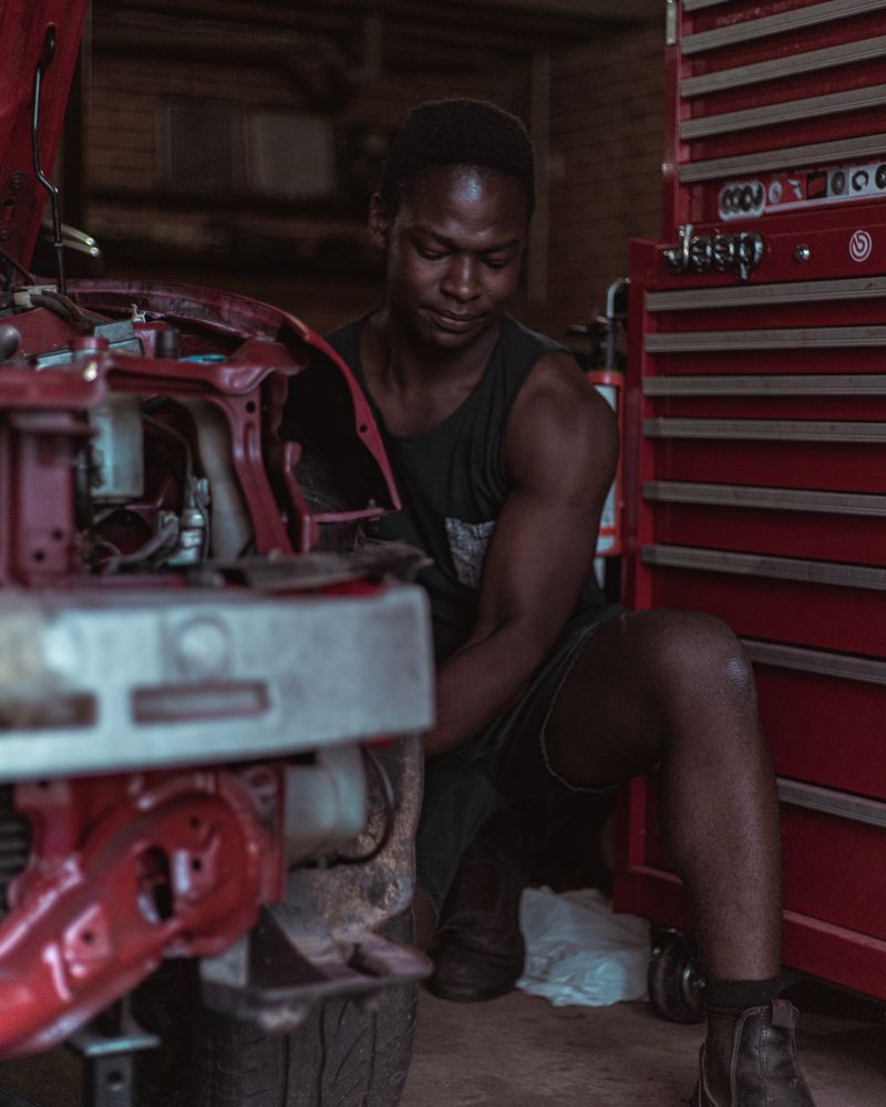 Technician working on a stripped machine assembly at a bench, tool chest open beside him.