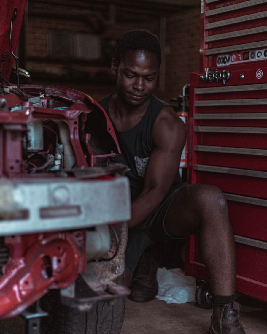 Technician working on a stripped machine assembly beside an open tool chest.