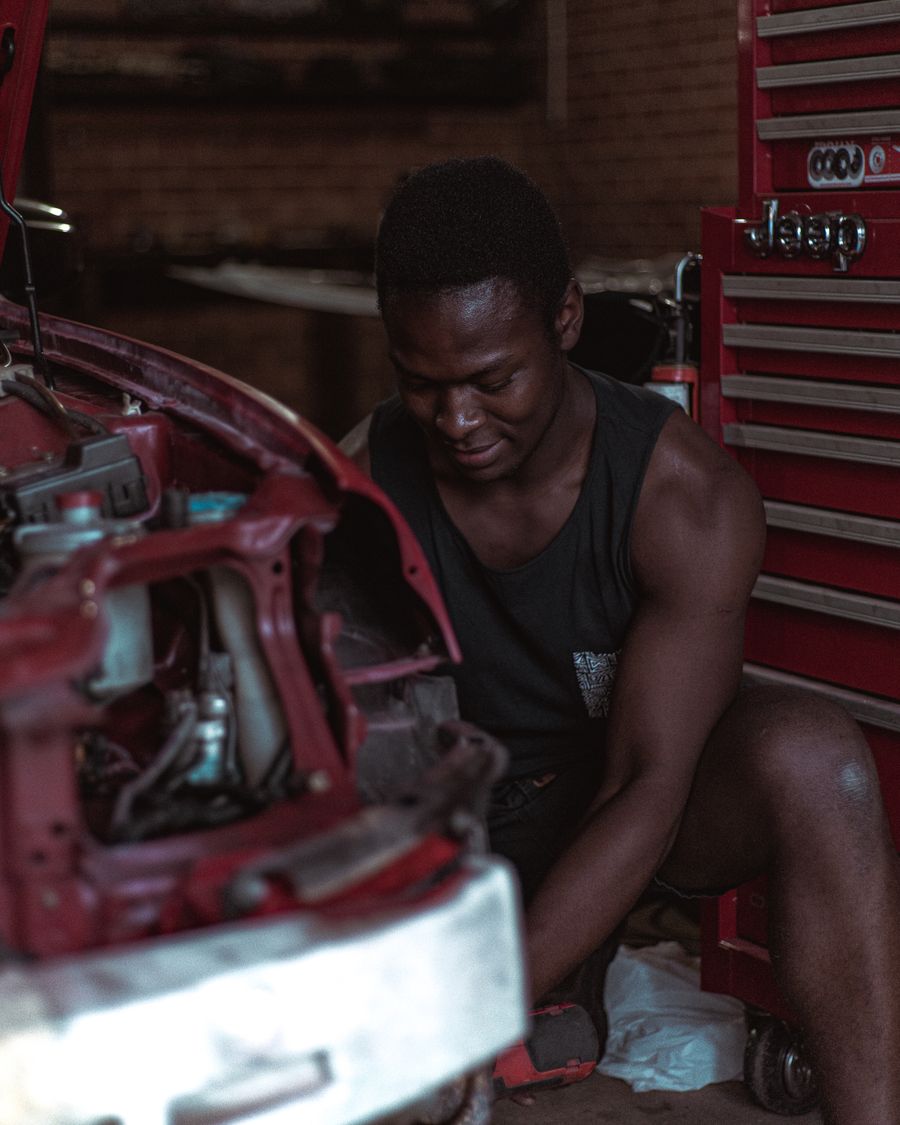 Ethnic repairman fixing car bodywork in a professional workshop