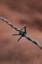 High angle detail of metal barbed wire fence against blurred background of field