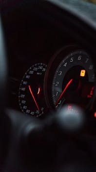 A close-up view of a car's illuminated speedometer and tachometer with a focus on the dashboard details.