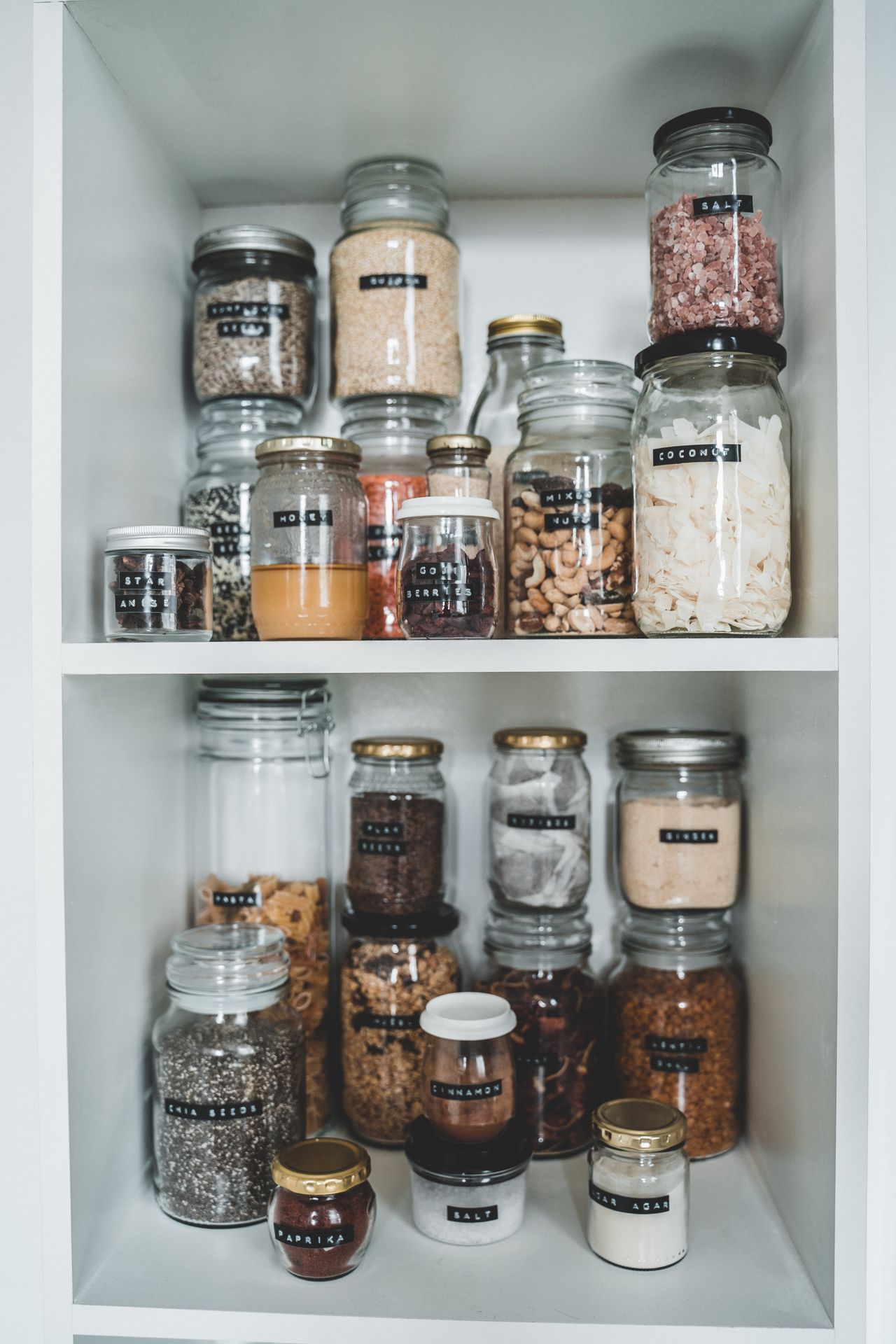 Well-organized pantry with labeled jars on wooden shelves