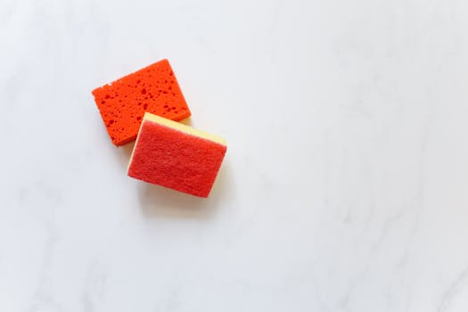 Two bright orange sponges suitable for cleaning against a white background.