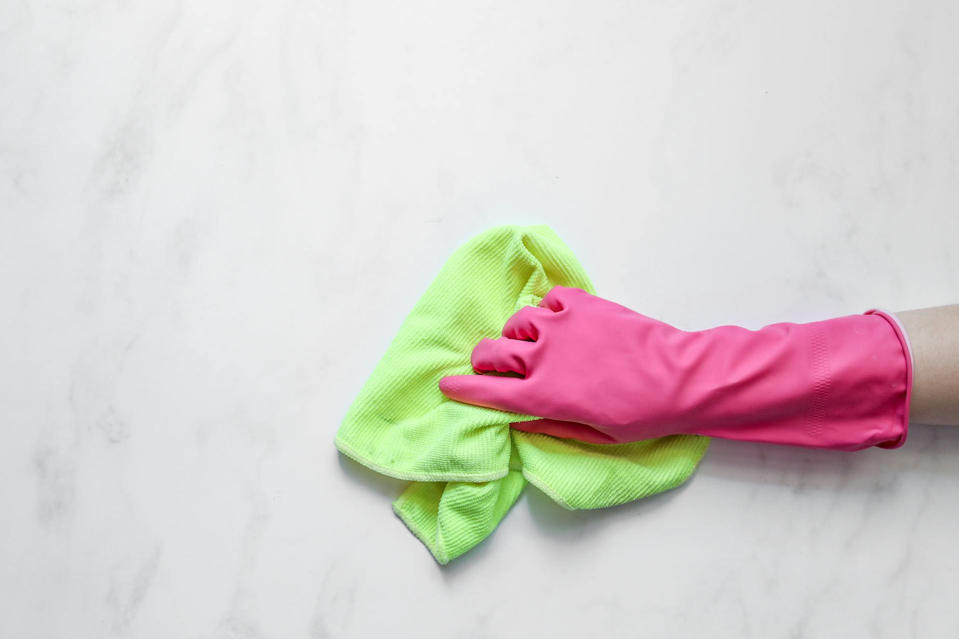 A Person Using Rubber Glove and Cleaning Cloth