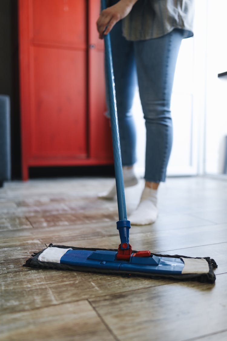 A Person Cleaning The Floor With A Mop