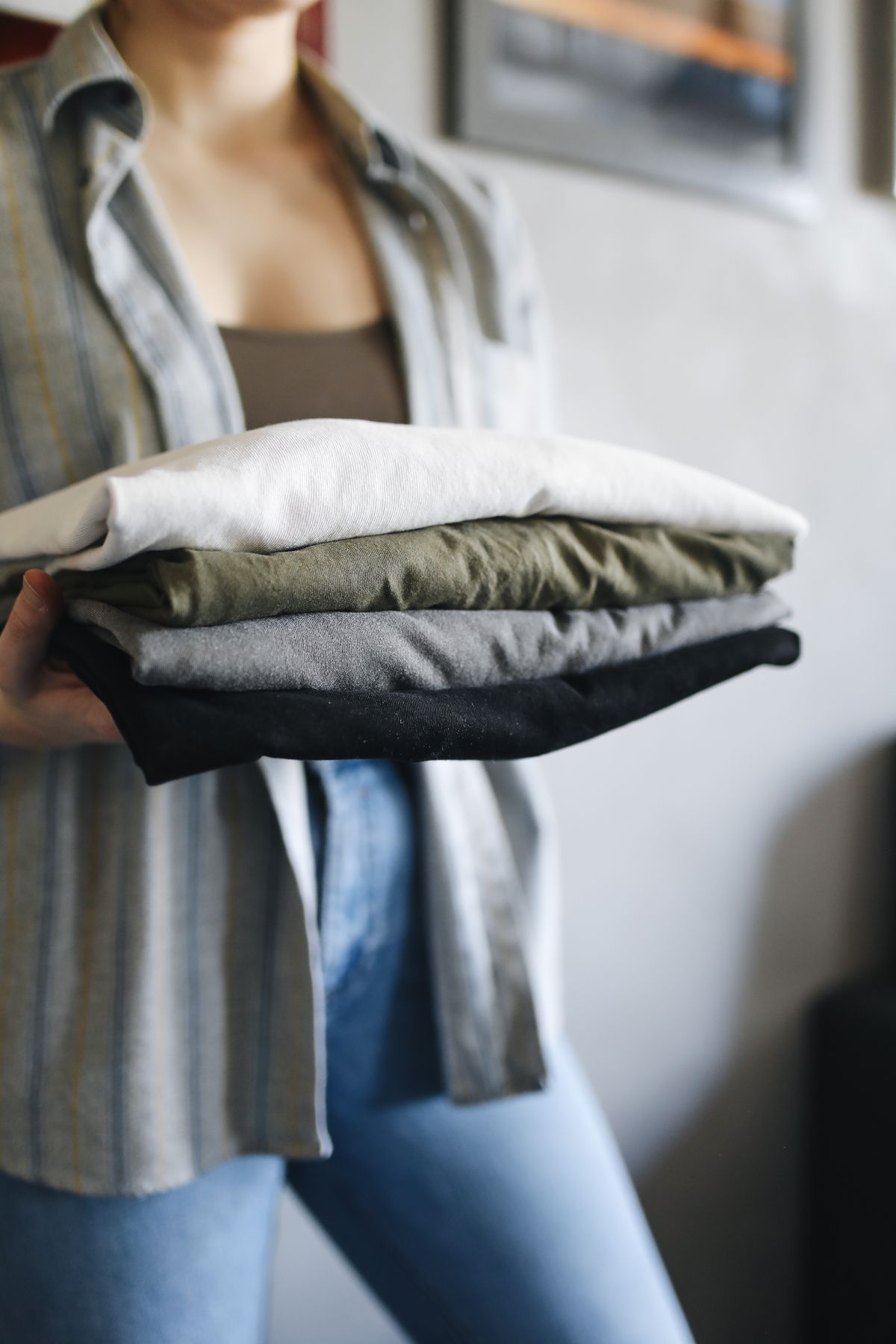 Hands holding stack of neatly folded shirts