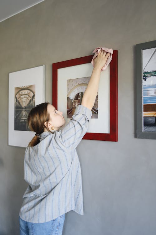Free A Woman Cleaning the Display Frames on the Wall Stock Photo