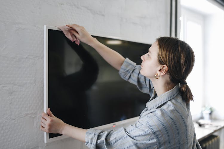 A Woman Wiping A Television With A Cloth