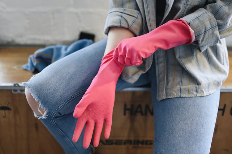 A Person Sitting On A Wooden Box Putting On Rubber Gloves