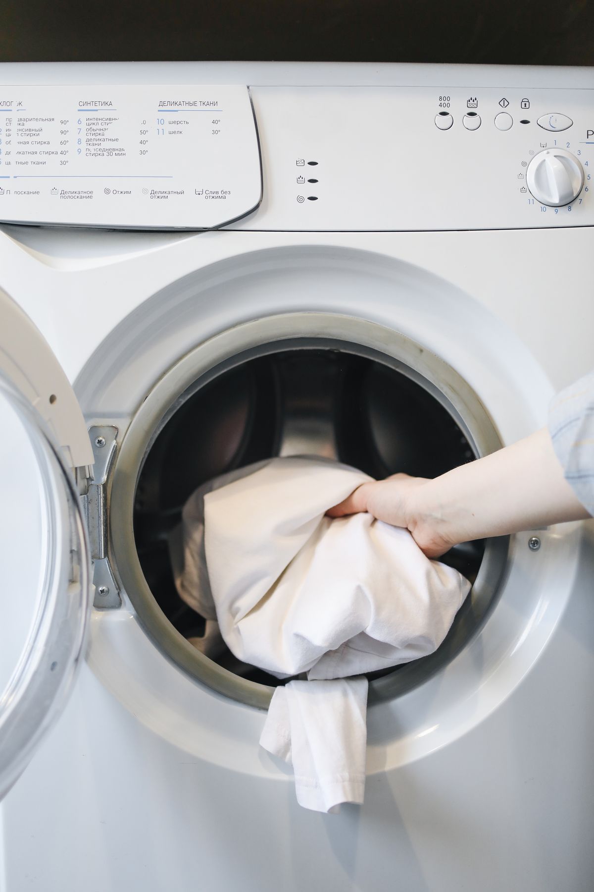 Pessoa colocando roupas na máquina de lavar