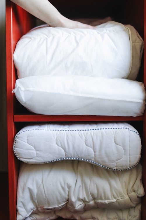 A Person Fixing the Bedding in a Shelf