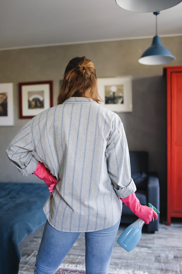 A Person Wearing Rubber Gloves Holding A Spray Bottle