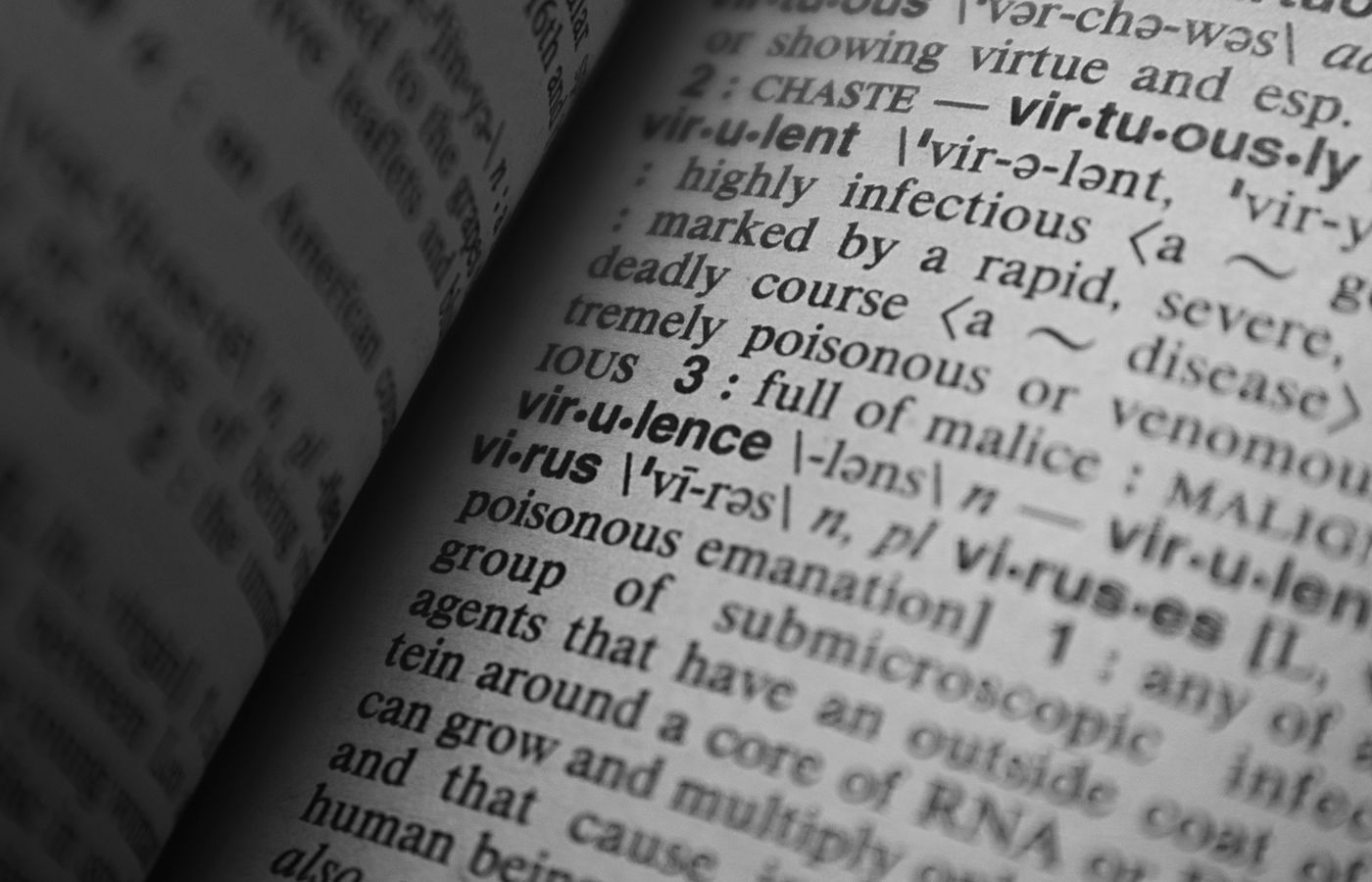 Black and white close-up of a dictionary page showing the definition of 'virus.'