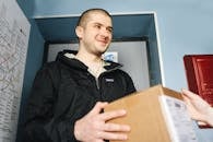 A Man in Black Zip Up Jacket Holding a Cardboard Box