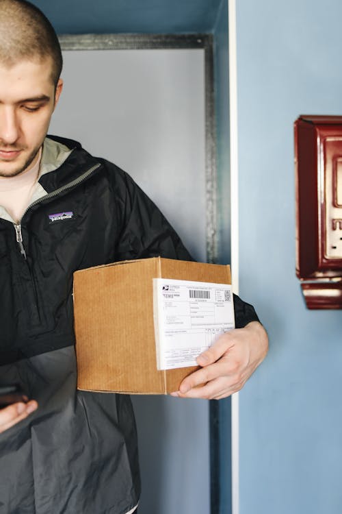 A Man in Black Jacket Holding a Cardboard Box