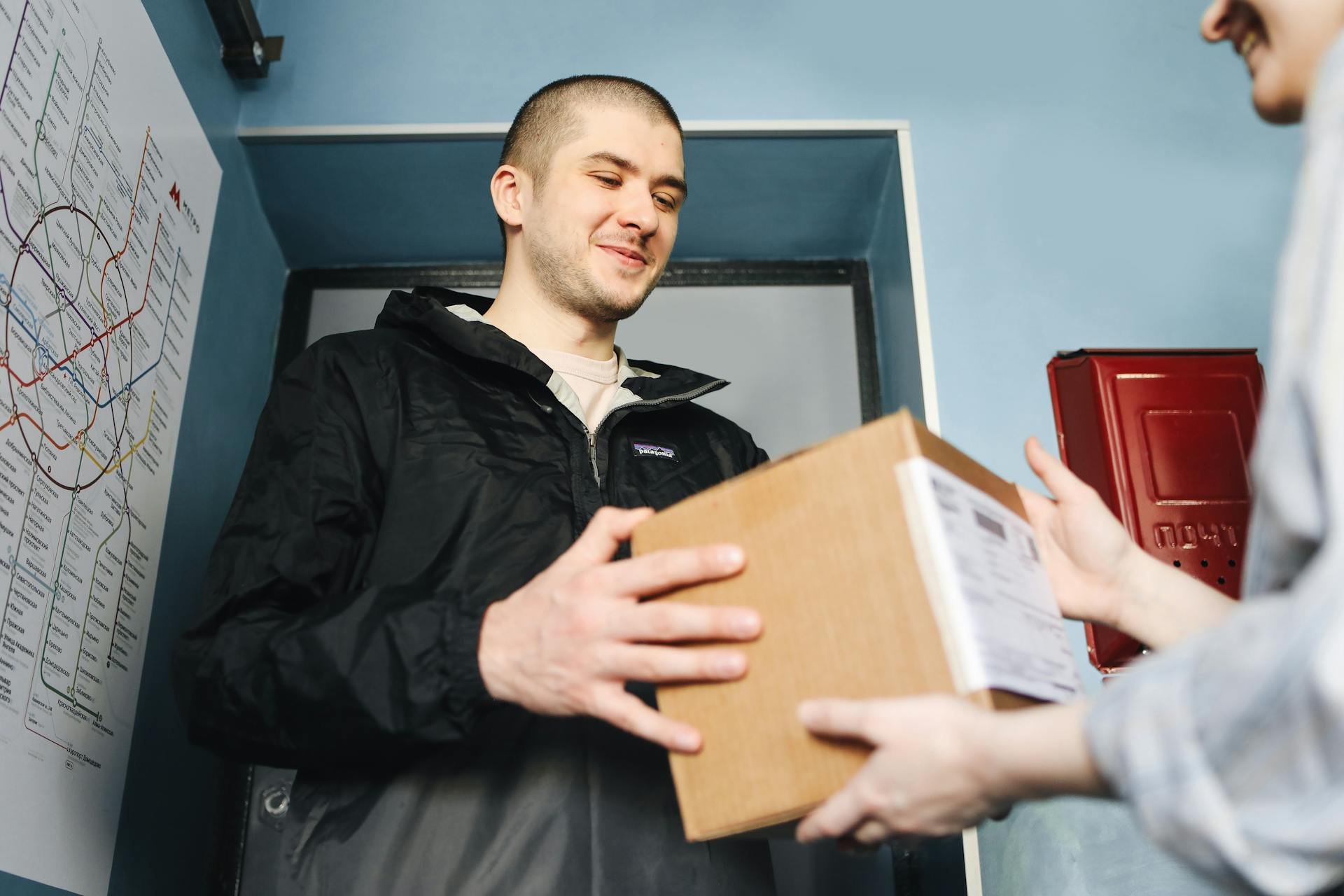 A Man Handing Over a Cardboard Box to a Person