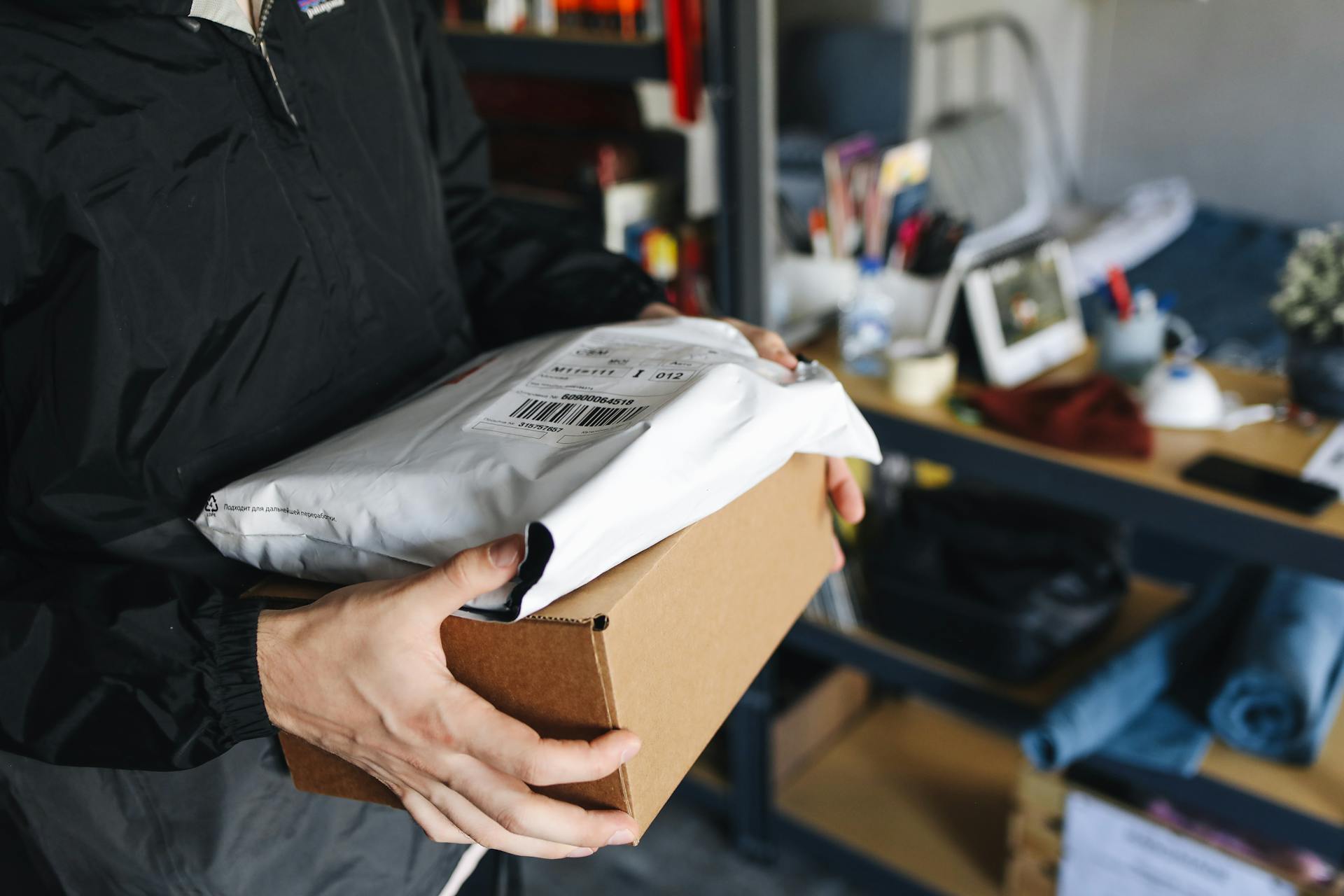 A Person Holding a Package in a Plastic Container and Cardboard Box
