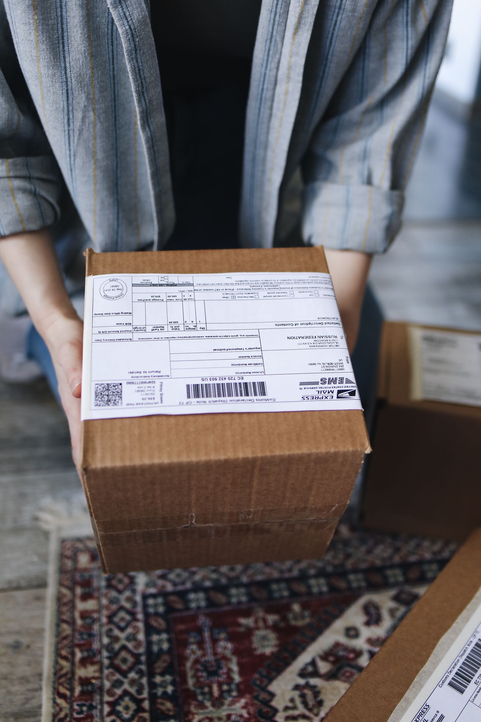 Person holding a labeled delivery package ready for shipment