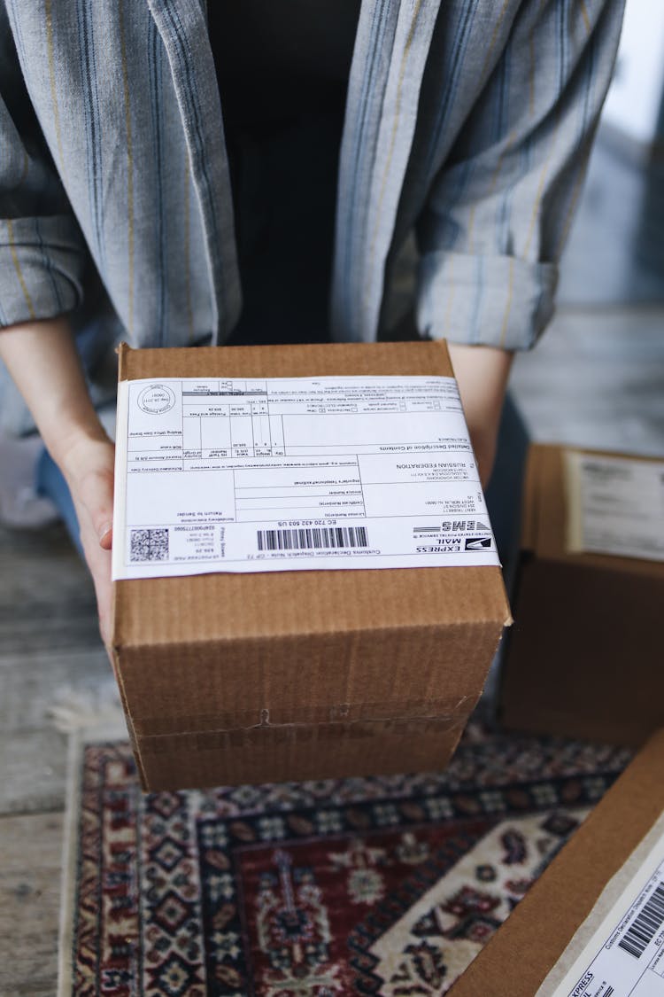 A Person Holding A Delivery Box