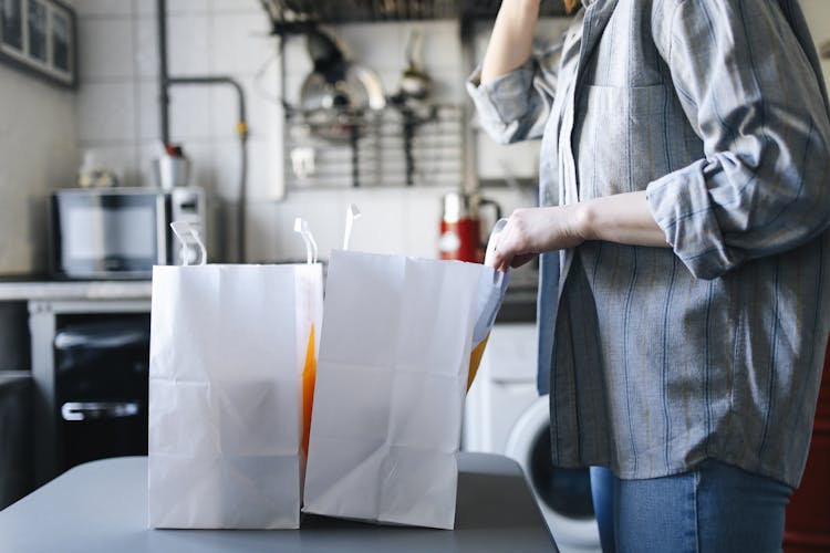 Person In Gray Shirt Holding White Paper Bag