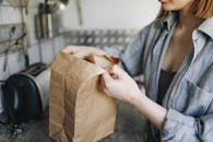 一名妇女在厨房里打开纸袋，特写镜头对准了取出的杂货