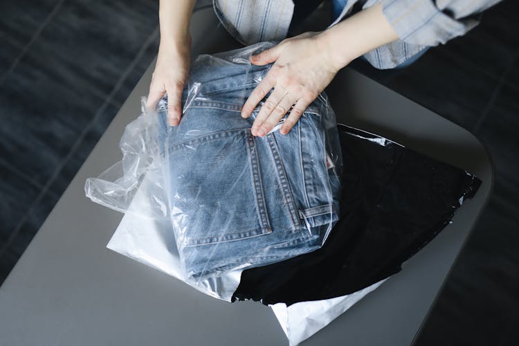 Woman Packing Jeans Into Plastic Bag