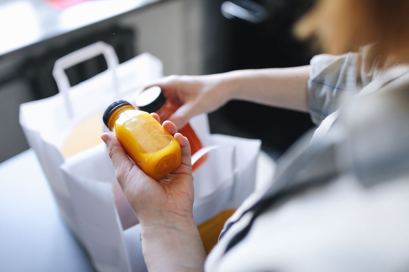 Bouteilles de jus sorties d'un sac de livraison et contrôlées à la main au moment de la réception