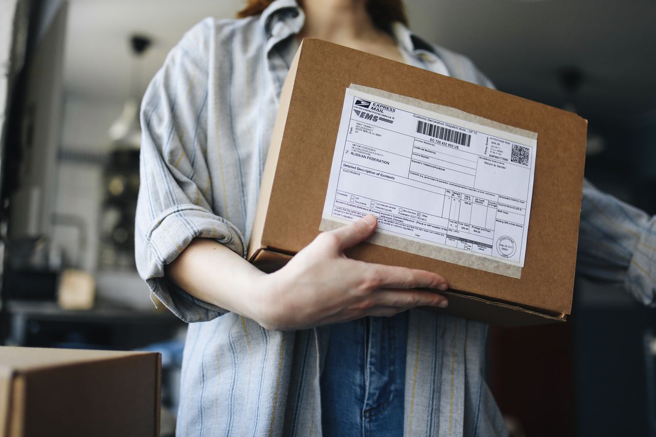 Close-up of a woman holding a parcel indoors, showcasing postal and delivery themes.