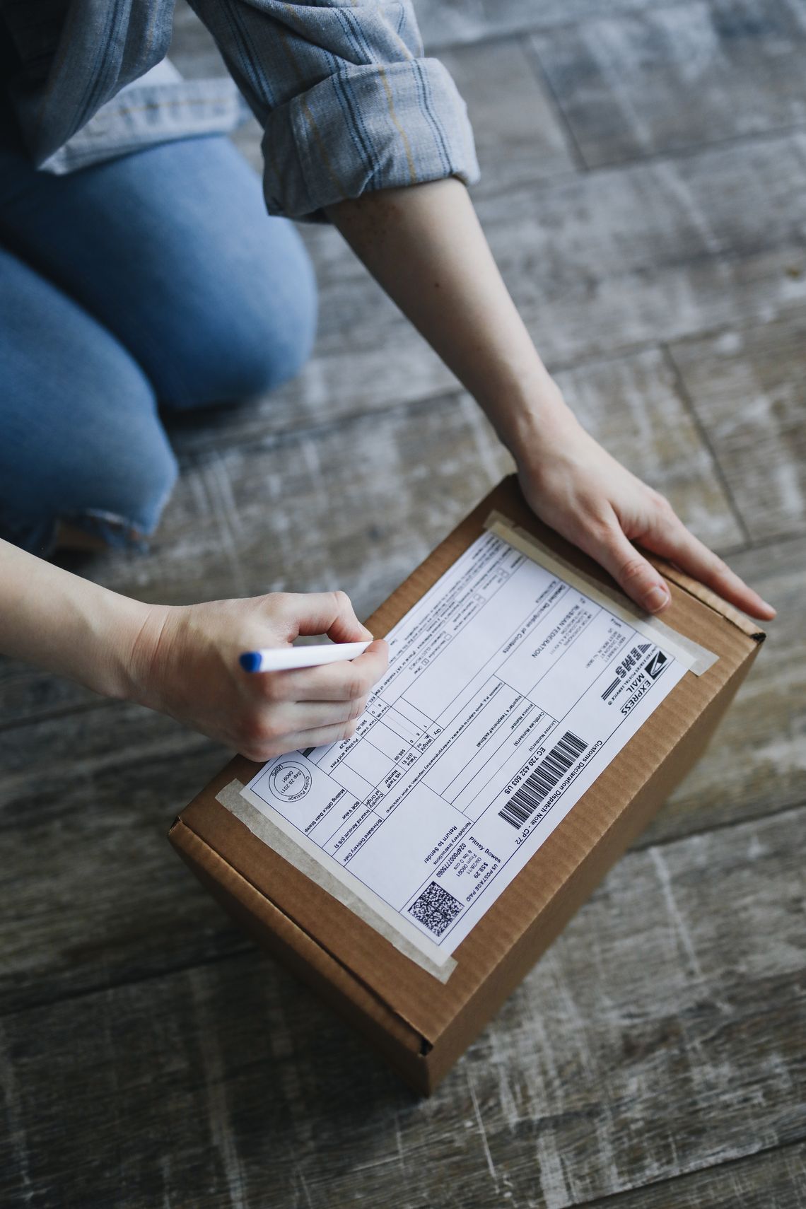 Hands preparing and labeling a cardboard package for shipment