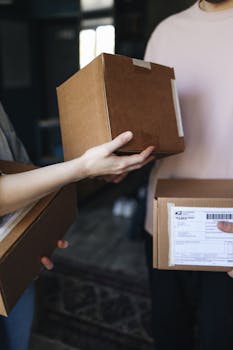 Close-up of hands exchanging cardboard delivery packages indoors.