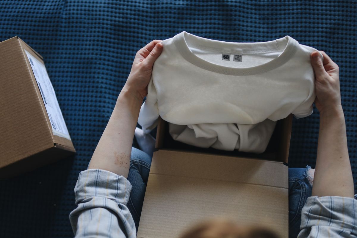 Customer opening a parcel containing a new clothing item