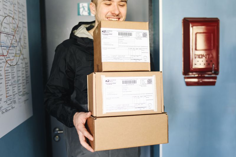 Courier holding stacked e-commerce parcels ready for delivery