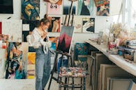 一位年轻的女艺术家在她充满活力的艺术工作室里作画，画布前摆满了鼓舞人心的艺术品